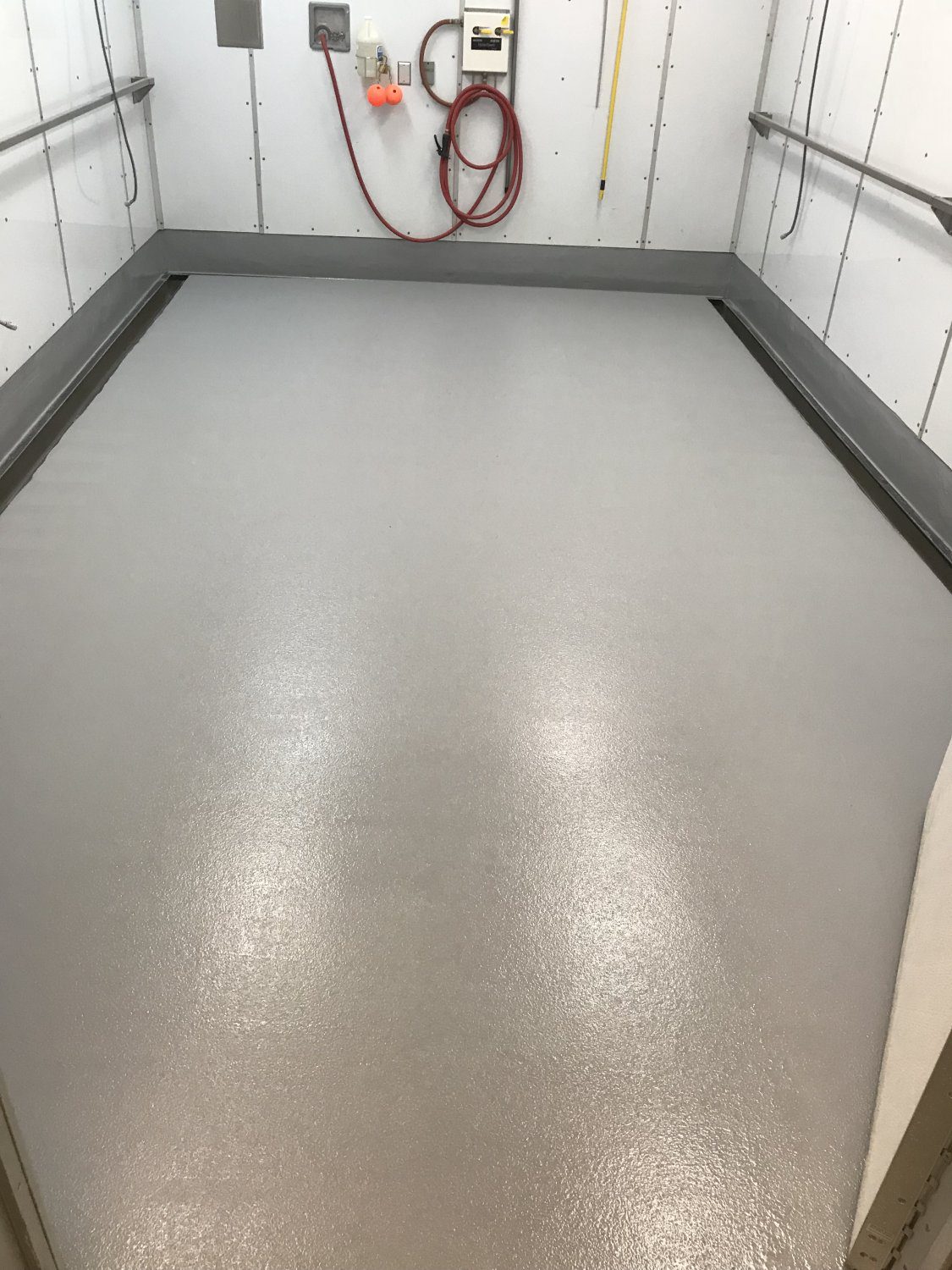 Gray-floored elevator space with safety rails.