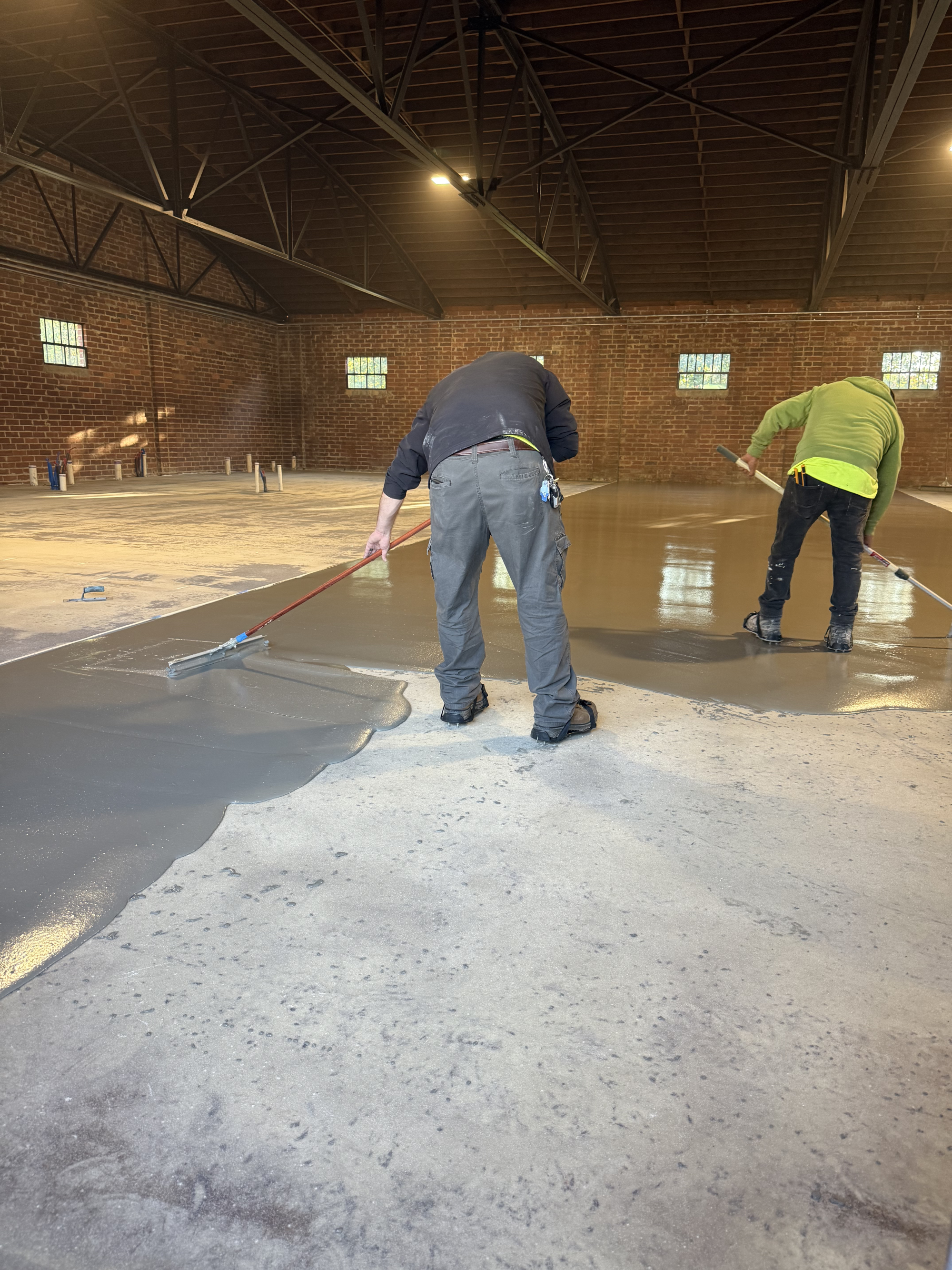 Workers smoothing concrete floor