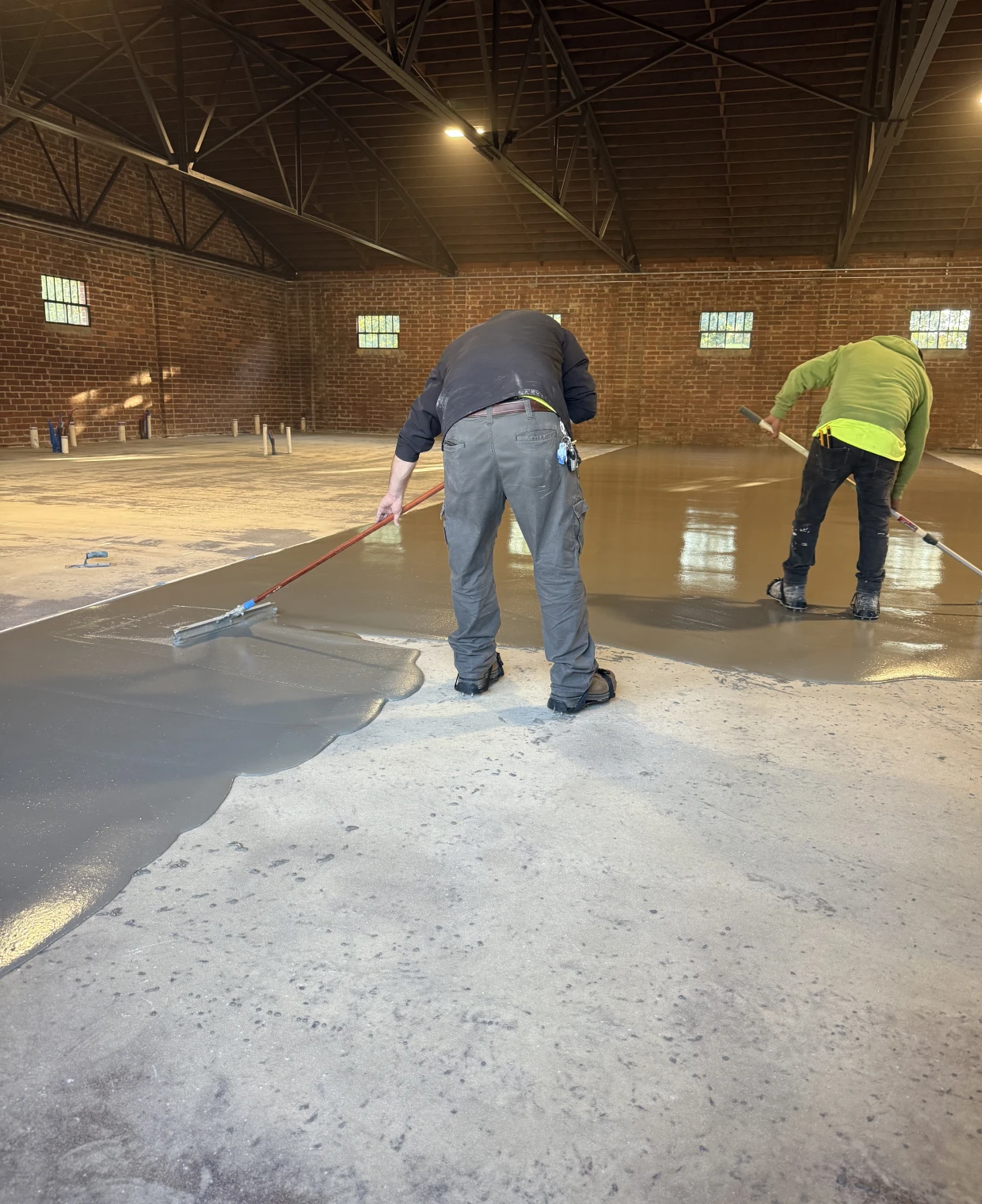 Workers smoothing concrete floor in warehouse